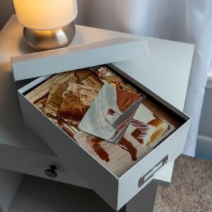 Open shoebox with nostalgic family photos on a bedside table.