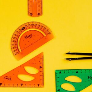 Colorful geometry tools and stationery set on a vibrant yellow background, ideal for educational themes.