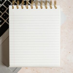 a notepad sitting on top of a laptop computer next to a keyboard