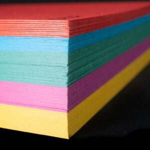 a stack of multicolored paper on a black background